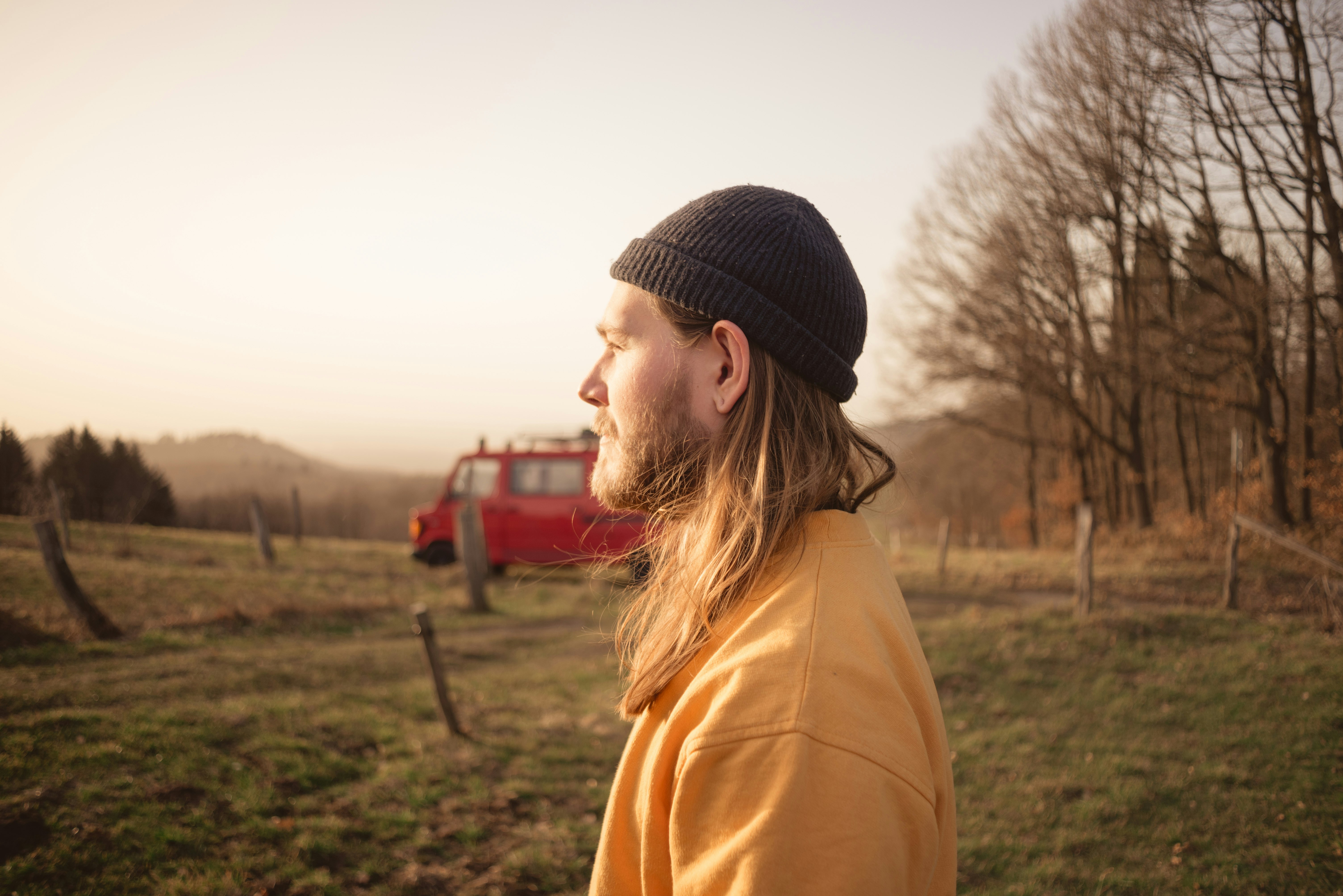 woman in brown jacket wearing black knit cap standing on green grass field during daytime